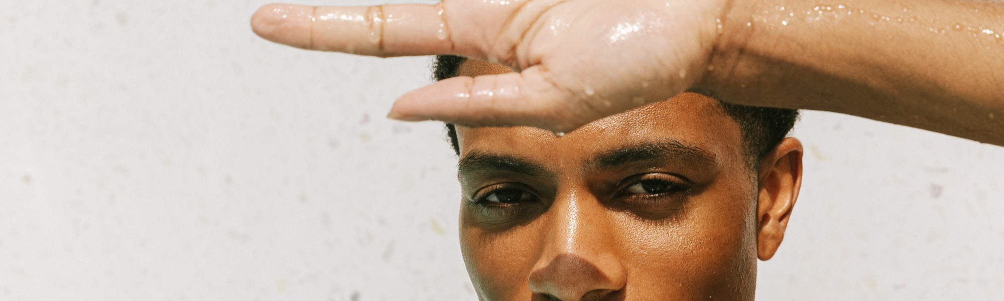 Un homme détendu au soleil avec une peau lumineuse, saine et protégée, illustrant les bienfaits d’une routine skincare apaisante et naturelle.