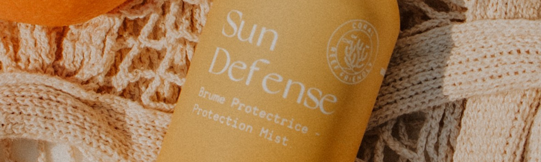 Flacon de Sun Defense MONO posé sur le sable au soleil, design épuré et naturel