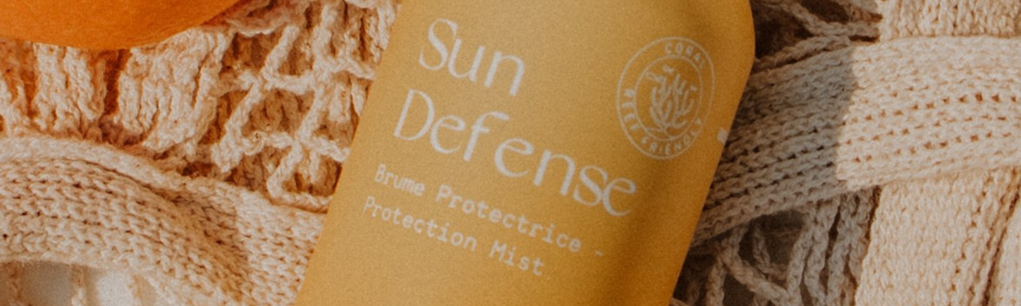 Flacon de Sun Defense MONO posé sur le sable au soleil, design épuré et naturel