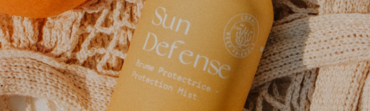 Flacon de Sun Defense MONO posé sur le sable au soleil, design épuré et naturel