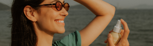 Femme appliquant la brume Sun Defense sur son visage sous le soleil, à la plage