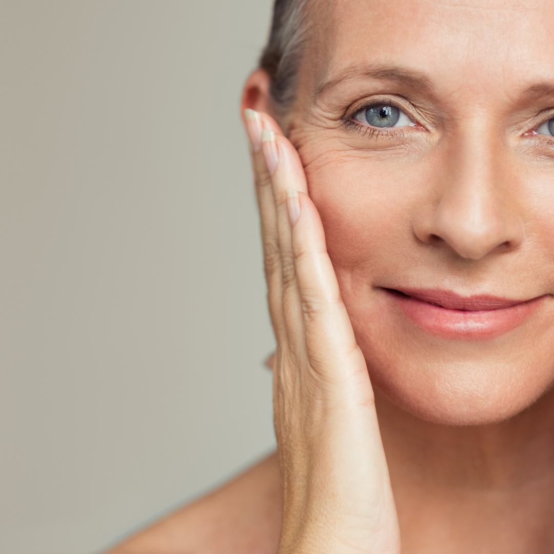 Woman applying sunscreen to her face to protect against premature aging.